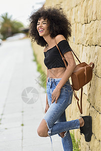 快乐的混合女人AFRO的头发户外笑女穿着休闲服装城市背景生活方式的图片