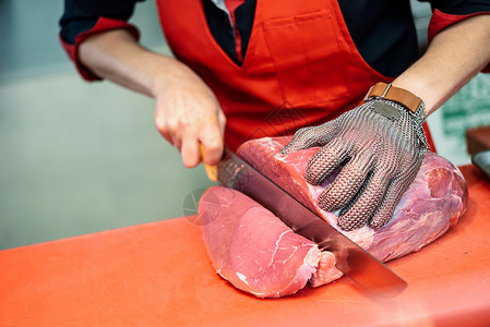 女屠夫肉店用金属安全网手套切鲜肉图片