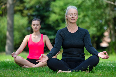 成熟健康的中女瑜伽老师瑜伽自然宁静的绿色环境中教轻女练瑜伽图片