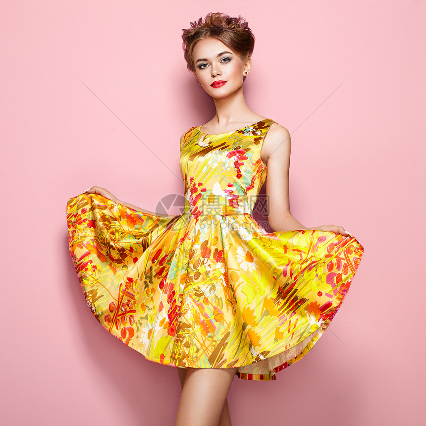 穿着花裙子的时尚轻女人的肖像穿着时尚夏季服装的女模特粉红色背景上摆姿势的女孩时尚的发型时尚照片金发女郎图片