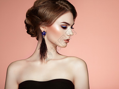 美丽的女人与大耳环流苏珠宝黑色完美的妆容优雅的发型蓝色化妆箭头图片