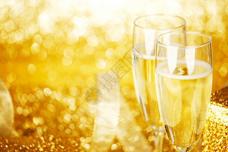 香槟眼镜礼品盒金色背景与闪烁灯图片