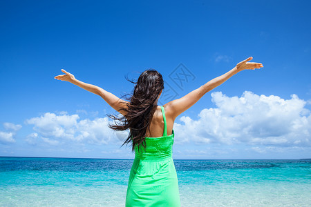 穿着绿色连衣裙的女人热带海滩上摆姿势,举手臂海滩上穿裙子的女人图片