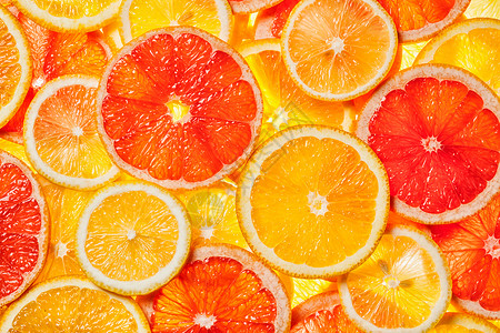 彩色柑橘类水果柠檬,橘子,柚子片背景背光五颜六色的柑橘类水果片图片