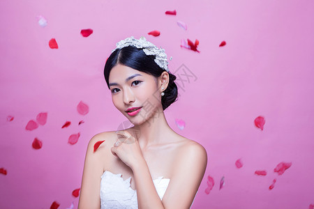 美丽新娘的肖像,玫瑰花瓣半空中,粉红色的背景图片