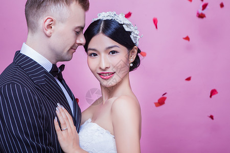 美丽的新娘与新郎站粉红色背景下的肖像图片