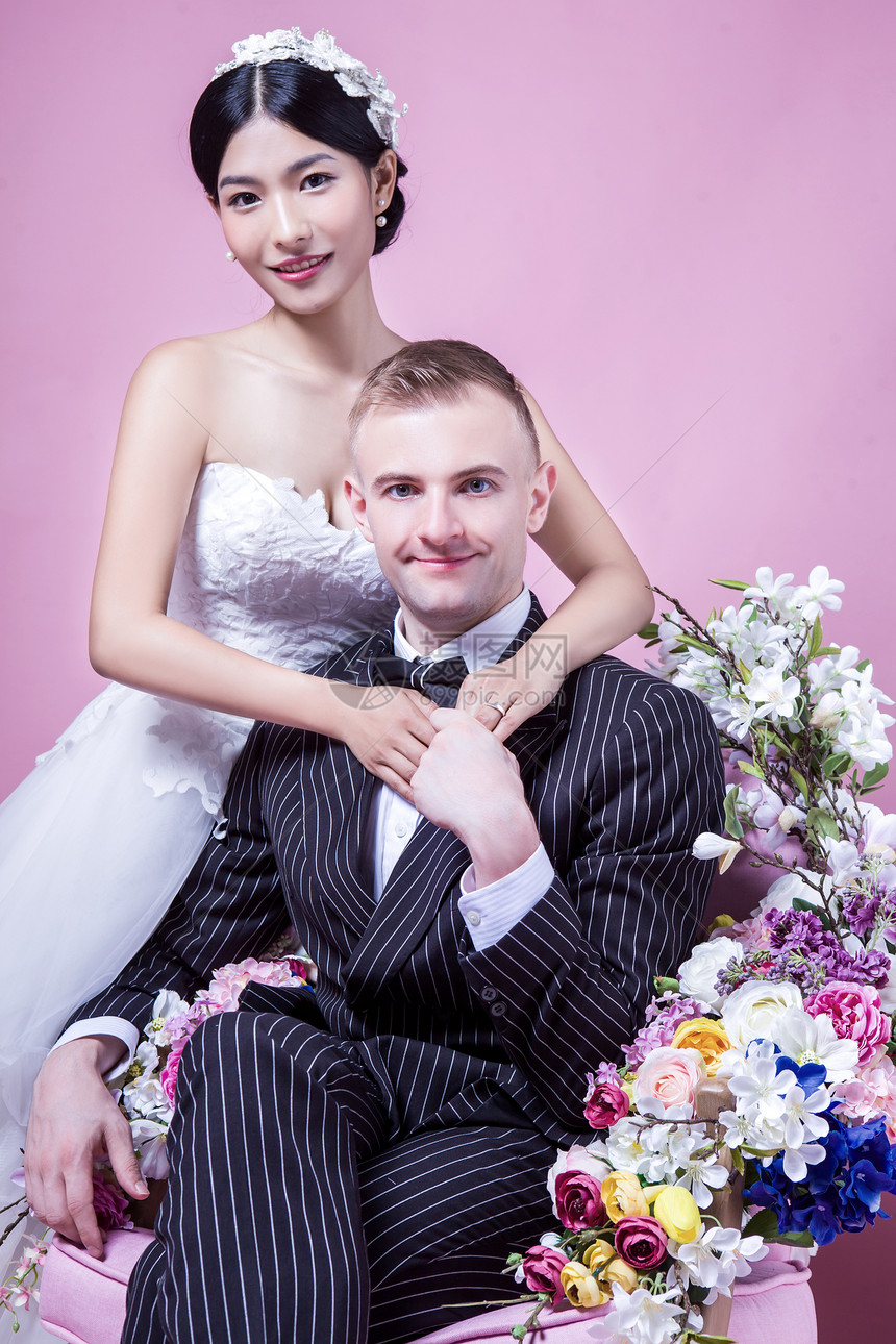 坐粉红色背景下的自信的新婚夫妇的肖像图片