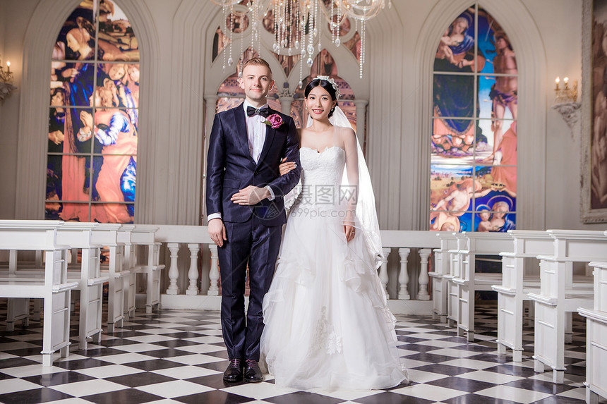 自信的新婚夫妇教堂里挽臂站立的肖像图片