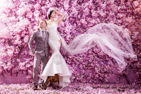新婚夫妇站墙上,满粉红色的花图片