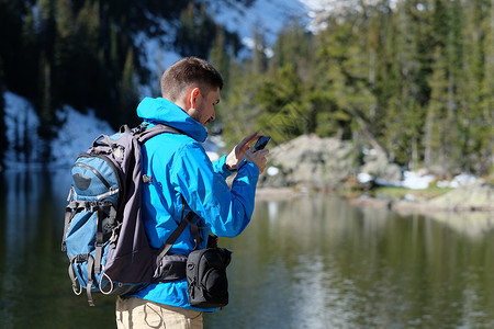 徒步旅行者与背包拍照与智能手机附近熊湖秋天的洛基山公园科罗拉多,美国图片