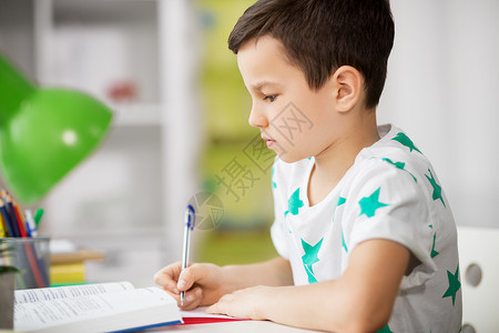 教育,童学校的男孩与教科书写作笔记本家里家里用教科书写作接近男孩图片