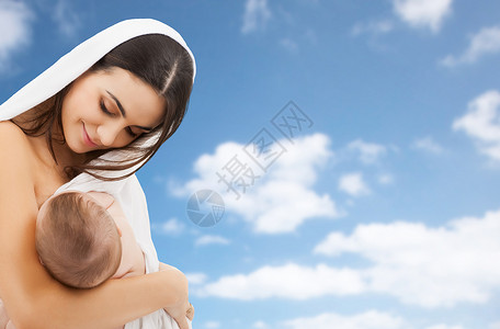 家庭,母乳喂养母亲的快乐的轻母亲与小婴儿吸吮乳房的天空背景母亲母乳喂养婴儿天空背景背景图片
