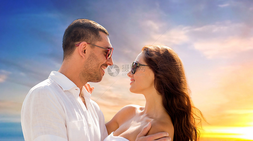 爱,夏天关系的幸福的微笑夫妇戴着太阳镜拥抱夜空的背景上幸福的微笑夫妇戴着太阳镜拥抱图片