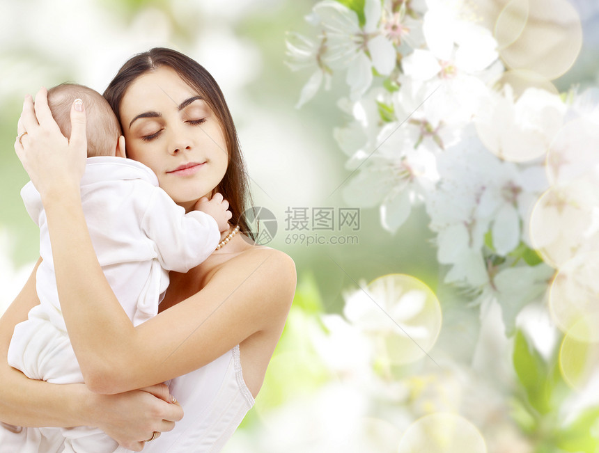 家庭母亲的快乐的轻母亲抱着小婴儿樱花背景下母亲带着孩子樱花背景下图片