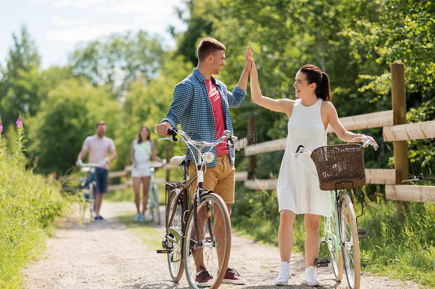 休闲生活方式的快乐的轻夫妇骑固定齿轮自行车夏天制造高五夫妇与自行车夏天制造图片