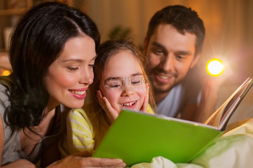 人们家庭的快乐的母亲,父亲小女儿家里晚上床上用手电筒看书快乐的家庭阅读书晚上床上家图片