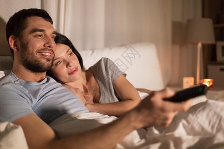 人,家庭休闲的快乐的夫妇晚上家床上看电视快乐的夫妇晚上家床上看电视图片