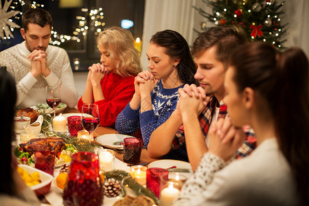 节日庆祝朋友牵手祈祷,同时家里吃诞晚餐朋友们回家吃诞晚餐祈祷图片
