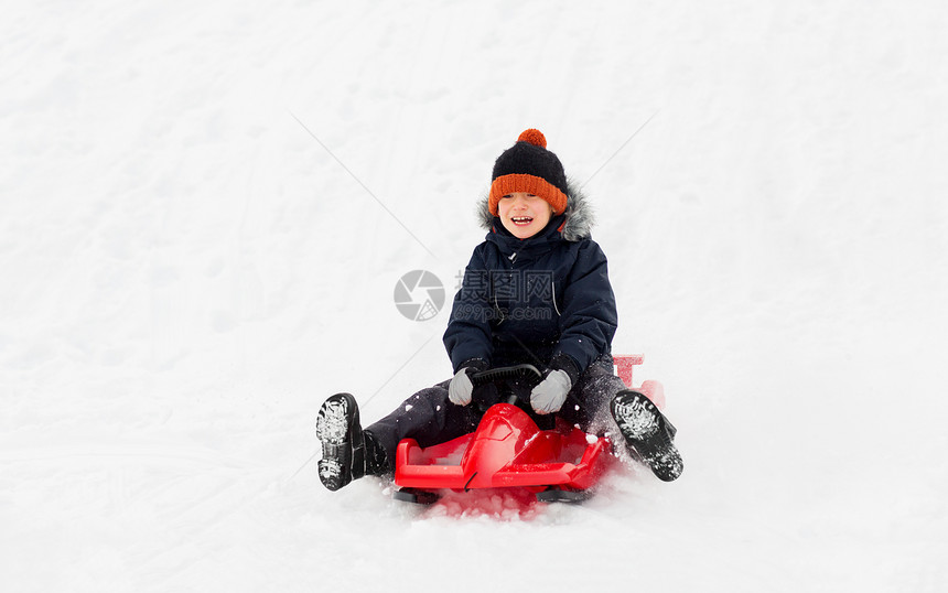 童,雪橇季节的快乐的小男孩滑雪橇下雪山冬天的户外快乐的男孩冬天乘雪橇滑下雪山图片