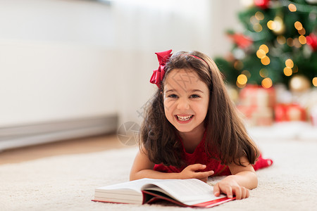 诞节,假期童的快乐的小女孩躺地板上,家看书诞节快乐的女孩家看书背景图片