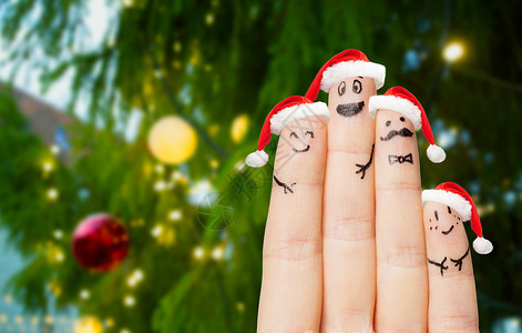 节日身体部位的四个手指与诞老人帽子诞树灯光背景诞老人帽子里的手指诞树上背景图片