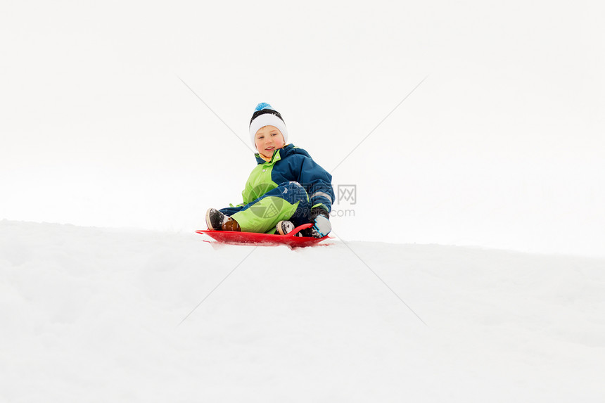 童,雪橇季节的快乐的小男孩滑雪橇下雪山冬天的户外快乐的男孩冬天乘雪橇滑下雪山图片