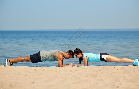 健身,运动生活方式的夫妇夏天的海滩上平板支撑夫妇夏天的海滩上平板支撑图片