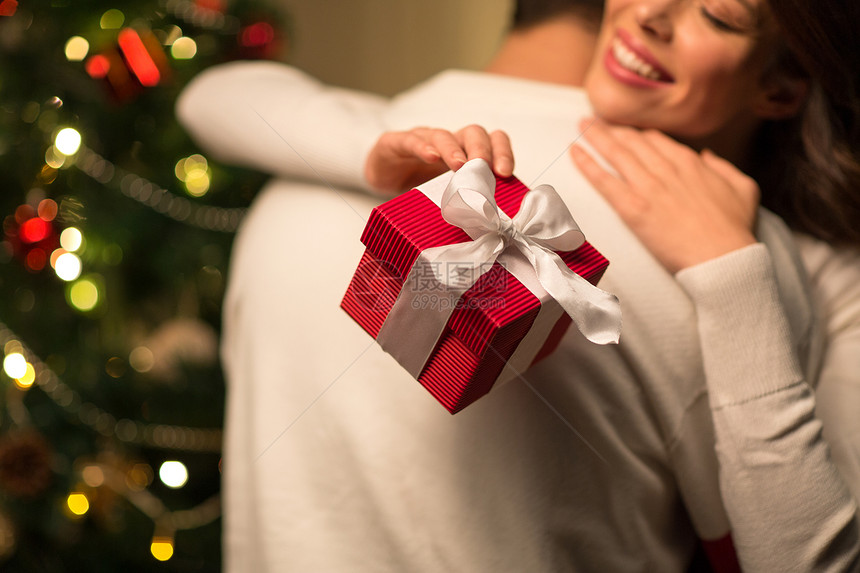 寒假人们的亲密的幸福夫妇与诞礼物拥抱家里亲密的夫妇与诞礼物拥抱图片
