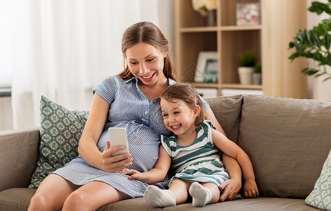 怀孕,人家庭的快乐的怀孕母亲小女儿家里智能手机怀孕的母女智能手机图片