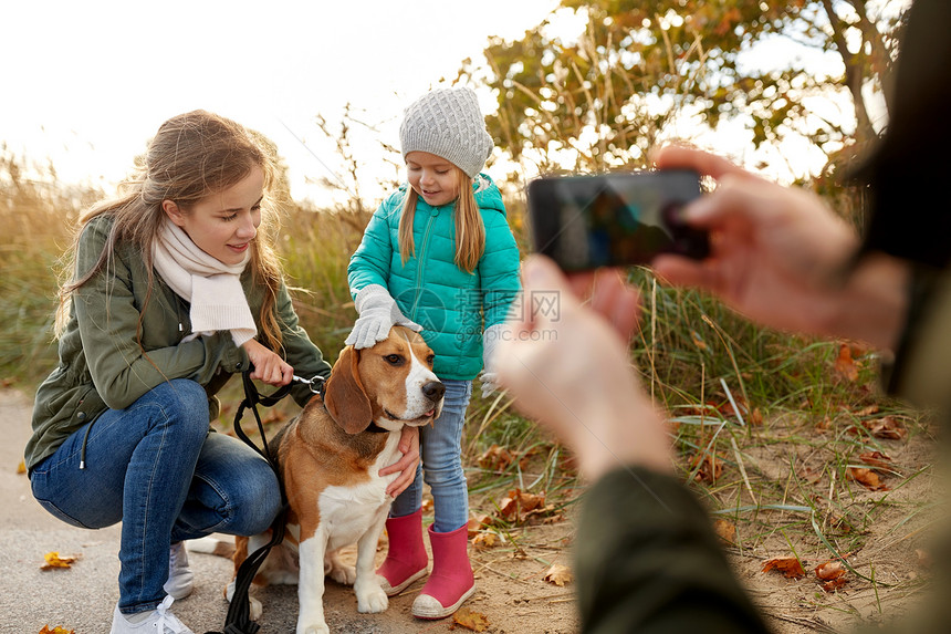 家庭休闲人的快乐的母亲父亲小女儿秋天的海滩上用智能手机拍照秋天的海滩上用智能手机拍摄家庭照片图片