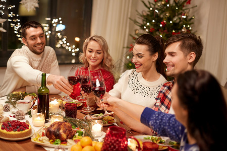 节日庆祝快乐的朋友家里吃诞晚餐,喝红酒碰杯朋友们庆祝诞节喝酒图片