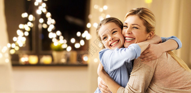 假期,人们家庭的快乐的微笑女孩与母亲拥抱沙发上的花环灯光背景快乐微笑的家人诞节家拥抱背景图片