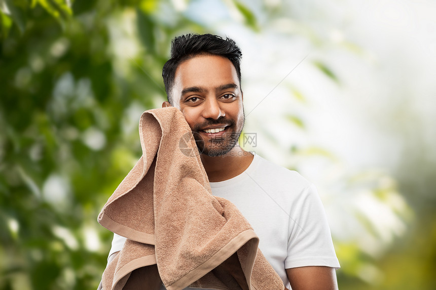 修饰人的微笑的印度男人,用浴巾绿色的自然背景上晒着他的脸带毛巾的印度男人自然背景图片
