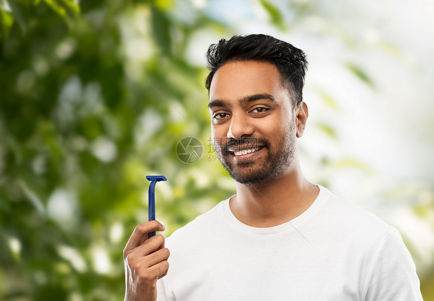 胡须剃须,美容人的微笑的印度男子与手动剃须刀刀片绿色的自然背景自然背景的剃须刀的印度男人图片