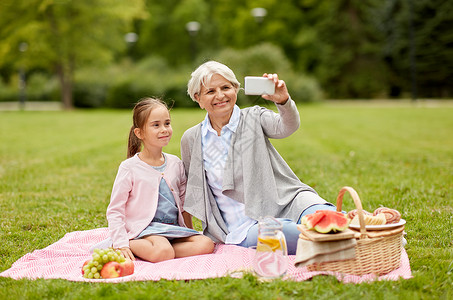 家庭,休闲技术快乐的祖母孙女野餐自拍智能手机夏季公园祖母孙女公园自拍图片