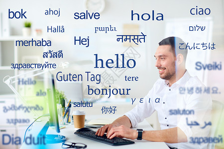 翻译商业技术微笑的男翻译商人办公室的电脑键盘上打字,用同的外语问候语计算机的人胜过外语的单词线高清图片素材
