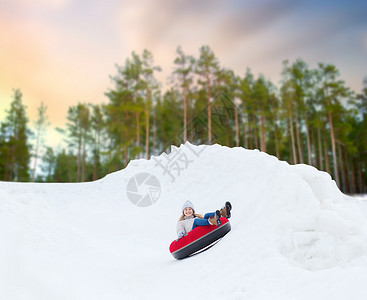 冬天,休闲娱乐活动的快乐的十几岁女孩滑下雪管下山快乐的少女雪管上滑下山背景图片