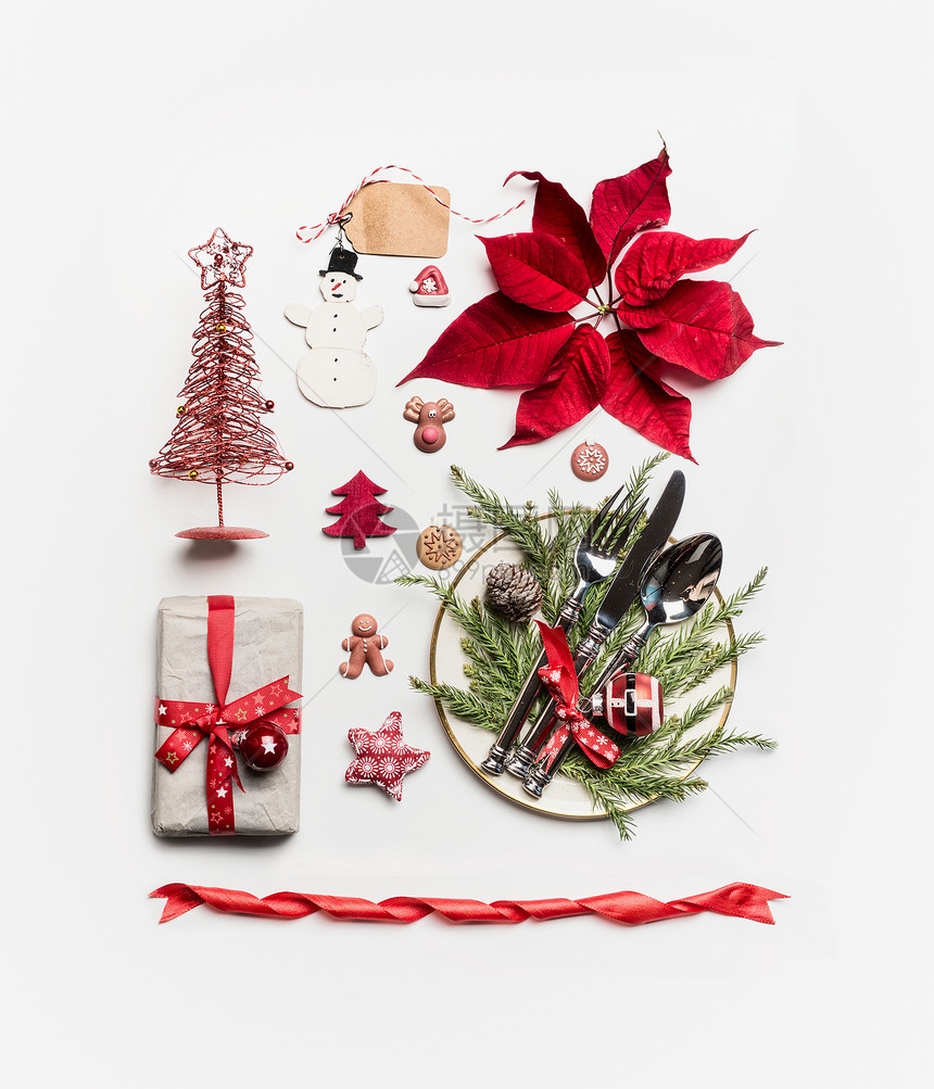诞节的各种节日物品礼物诞树餐具装饰品的餐桌冷杉枝松果白色背景下的品红平躺,俯视图片