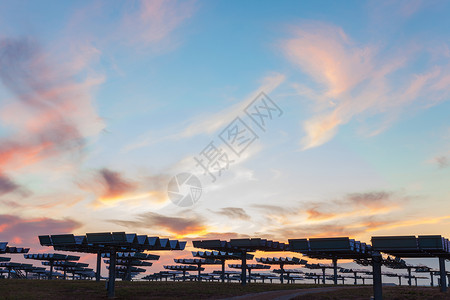 日出日落时提供替代绿色能源的光伏太阳能电池板领域背景图片