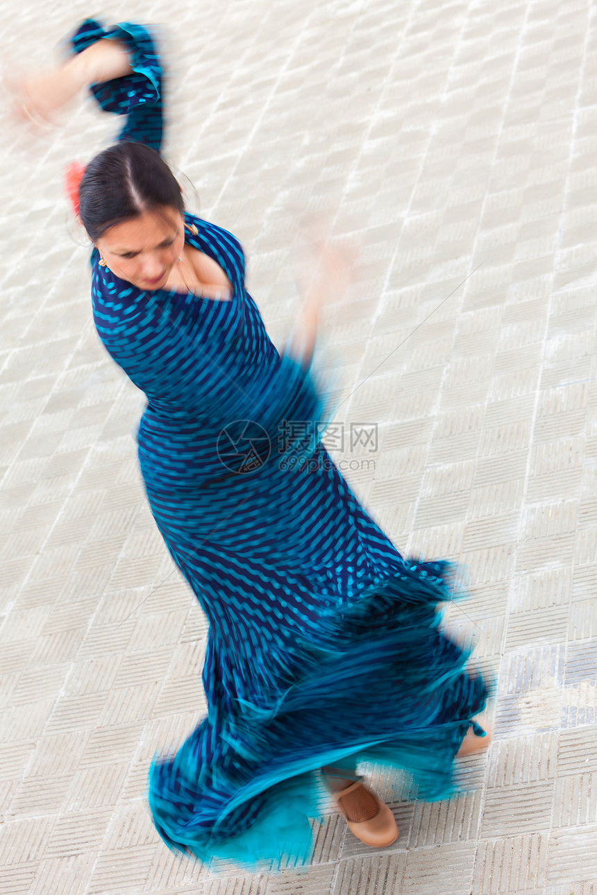 动作模糊慢快门速度拍摄的女传统西牙弗拉门戈舞蹈跳舞的蓝色波尔卡圆点连衣裙图片