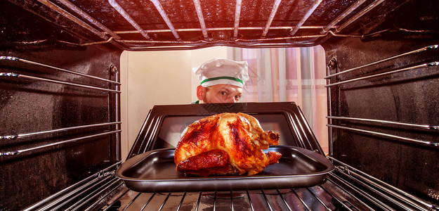 感恩节火鸡厨师厨师烤箱里准备烤鸡,烤箱看烤箱里饭背景