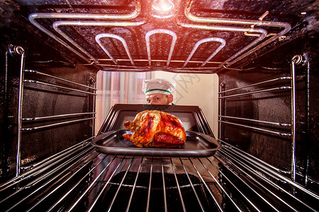 感恩节火鸡厨师厨师烤箱里准备烤鸡,烤箱看烤箱里饭背景