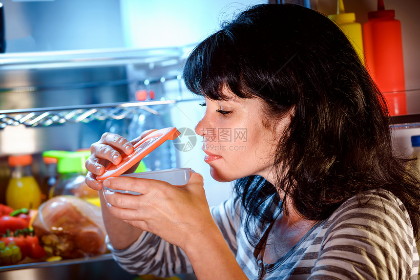 女人打开冰箱,闻了闻容器的食物图片