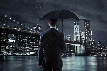 轻的经理带着雨伞夜城市背景上图片