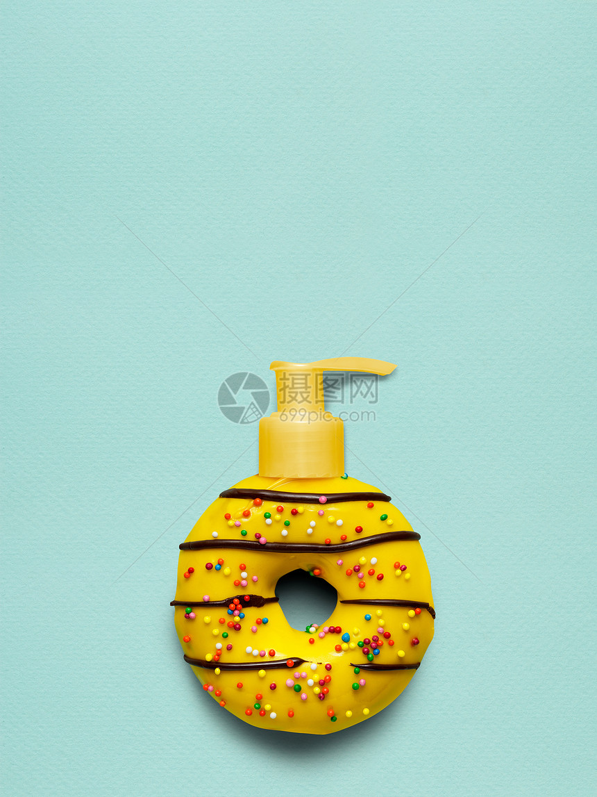 创造的静物生活,个美味的甜黄甜甜圈与化妆品泵分配器蓝色背景图片