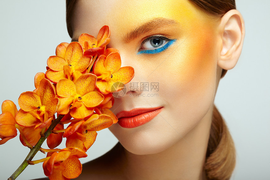 美丽的轻女子兰花的肖像黑发女人,化妆豪华完美的皮肤睫毛化妆品眼影橙色的花图片