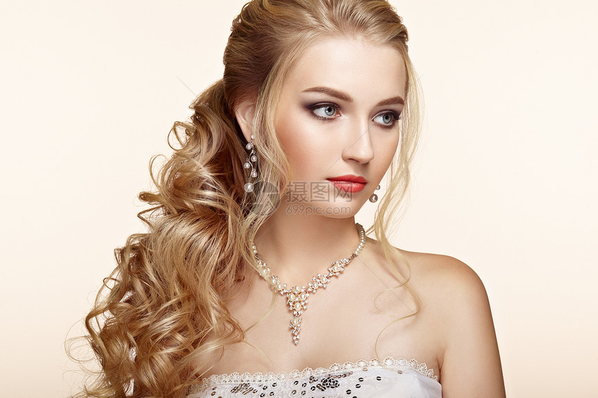 头又长又亮的卷发的金发女孩漂亮的模特,留着卷曲的发型护理美容美发产品完美的化妆珠宝图片