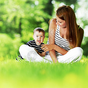 母亲女儿坐春天公园的草地上公园里的母亲女儿图片