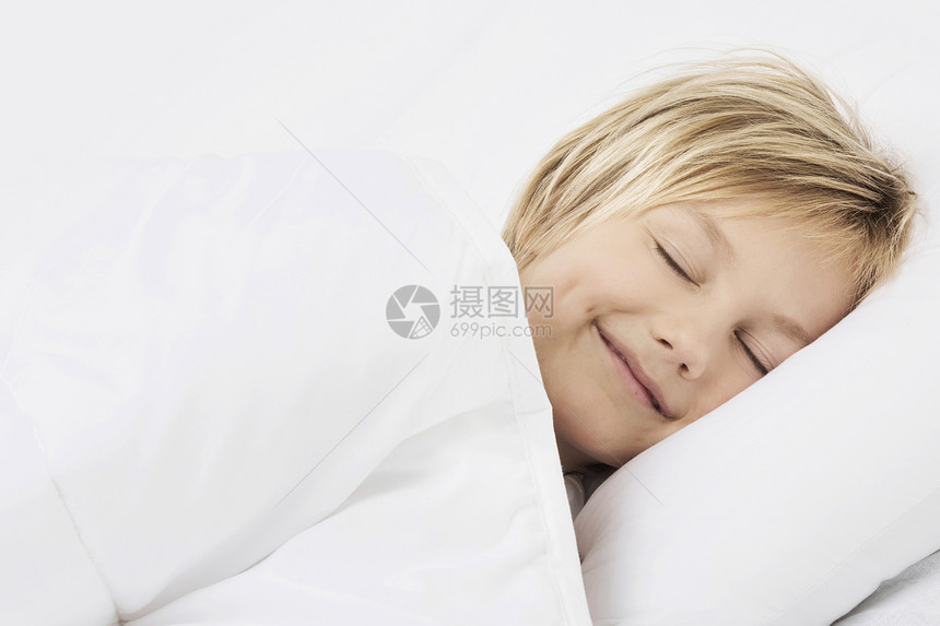 男孩睡床上微笑可爱的小男孩安静地睡床上,微笑着看个梦图片