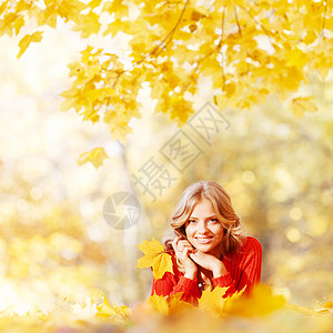 美丽的轻女人躺秋天公园的黄叶上女人躺秋天的公园里图片